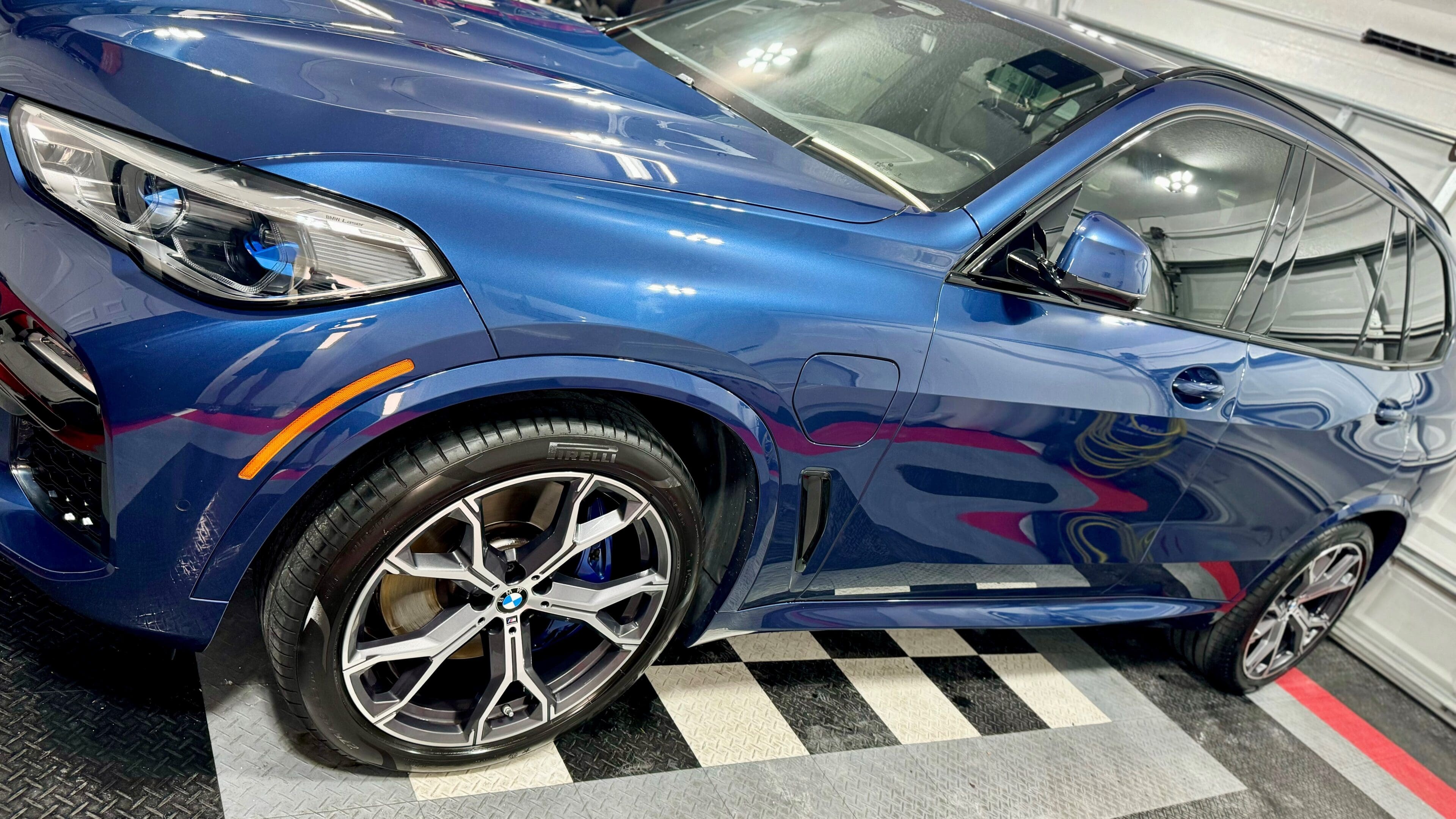 A blue bmw parked on top of a checkered floor.